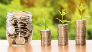jar of money and three stacks of coins with plants growing from them to represent earning money