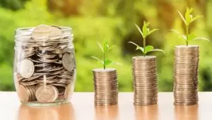 jar of money and three stacks of coins with plants growing from them to represent earning money
